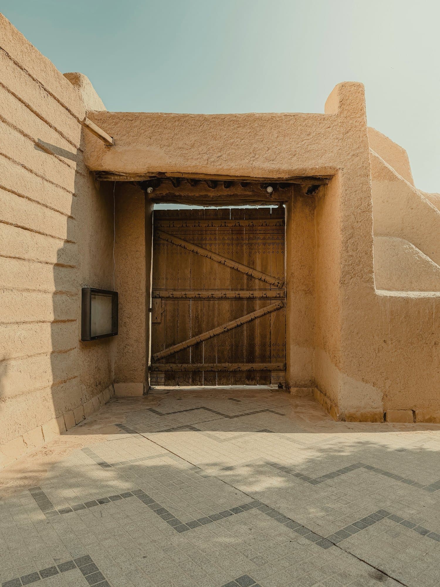 A carved wooden Najdi door set in a mud-brick wall